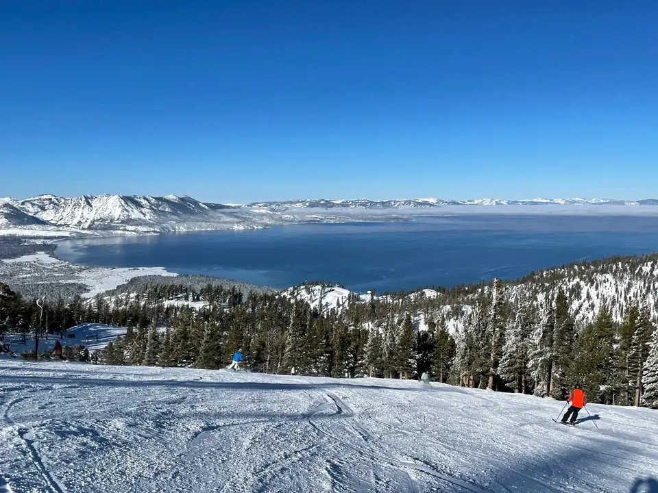 Skiers on a groomed run high above Lake Tahoe on a clear winter day
